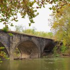 Tranquil river scene with stone bridge and autumn trees