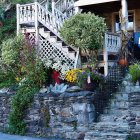 Stone house with wooden balcony and colorful flowers in soft sunlight