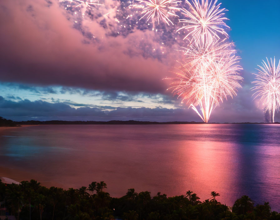 Colorful fireworks illuminate calm sea at dusk