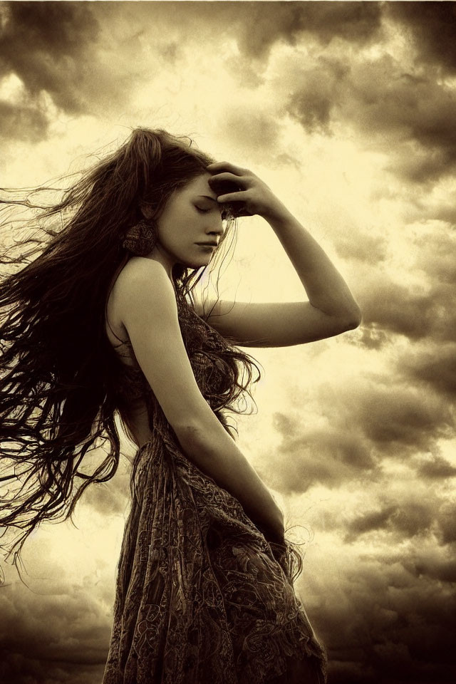 Profile of woman with long hair against dramatic cloudy sky