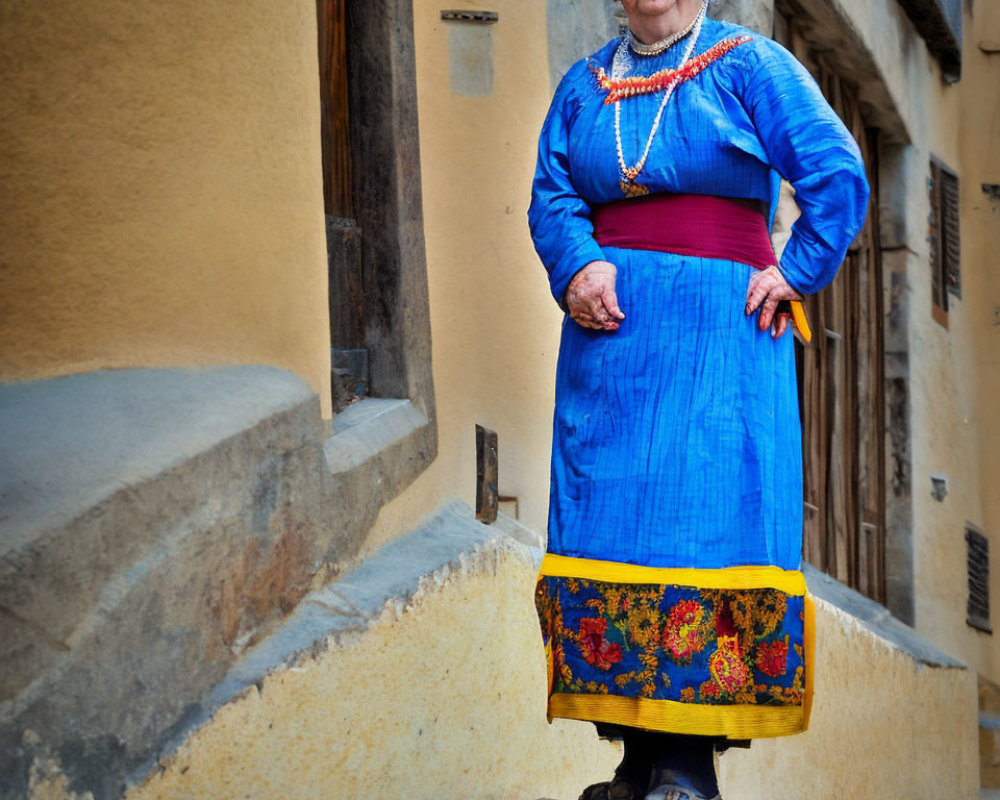 Elderly woman in traditional blue dress with floral embroidery on stone step