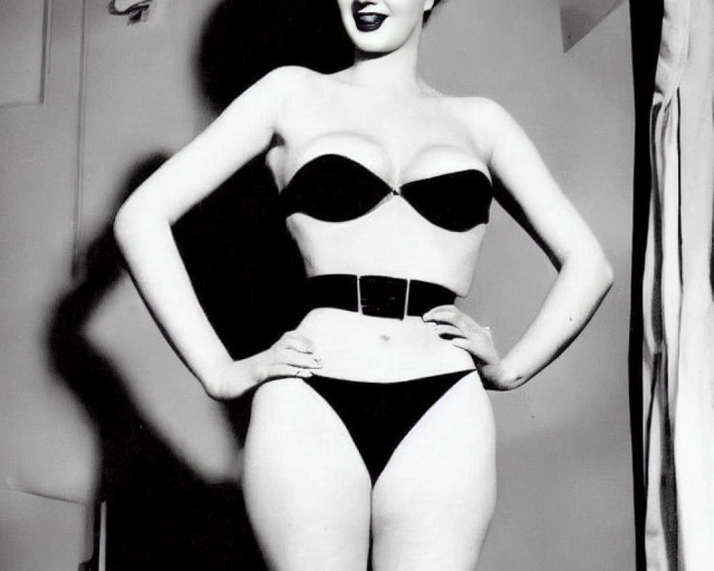 Vintage black and white photo of woman in retro swimsuit with bow in hair