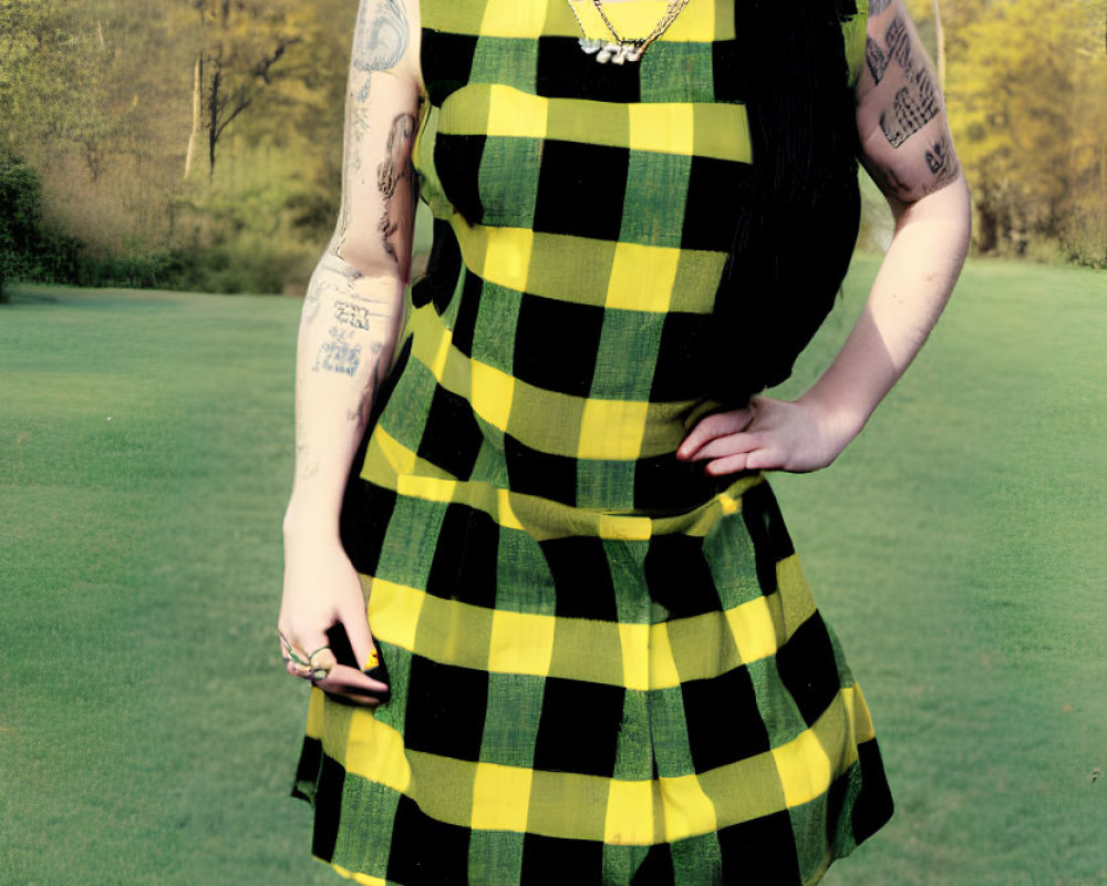 Black-haired person with tattoos in checkered dress and yellow socks holding yellow item in park