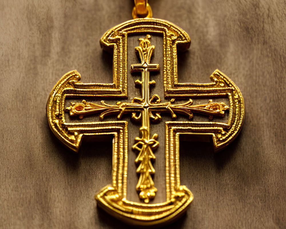 Intricate Gold Embroidered Cross Pendant on Chain Against Brown Background