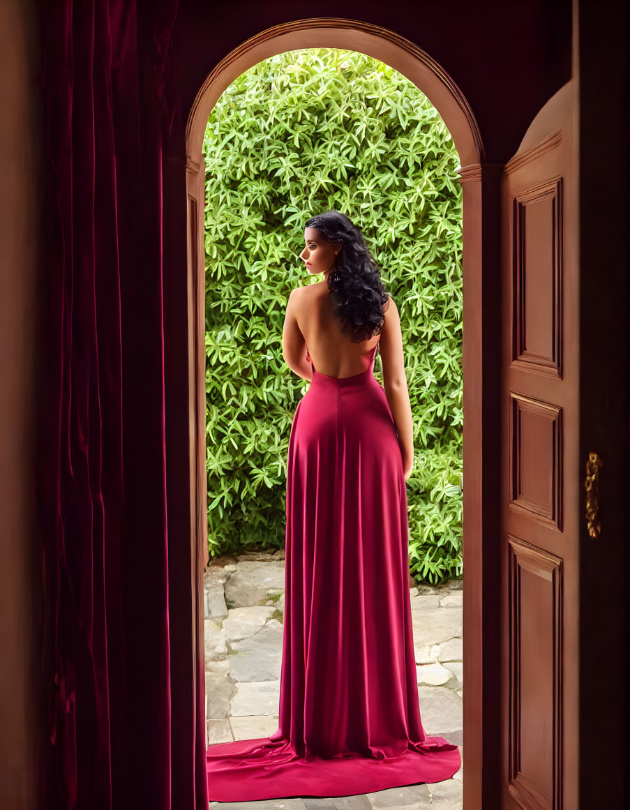 Woman in Burgundy Gown at Open Arched Doorway gazes at Lush Garden