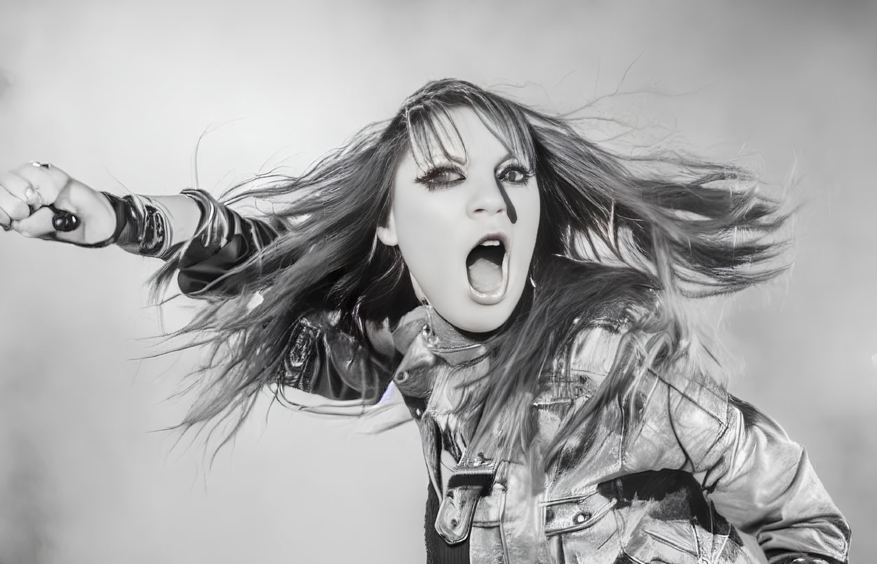 Monochrome image of woman in leather jacket shouting with flowing hair