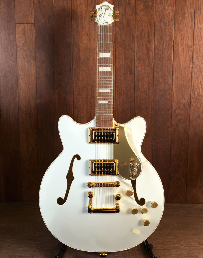 White Hollow Body Electric Guitar with Gold Hardware on Dark Wood Background