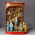 Ornate golden and blue figurines in clear cylindrical case with red and gold accents