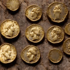 Ancient gold coins with embossed portraits on wooden surface