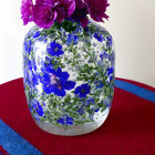 Colorful Vase with Blue Floral Patterns and Pink Roses on Red and Blue Patterned Table