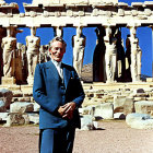 Man in Blue Suit at Ancient Greek Ruins with Carved Statues