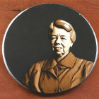 Metal medallion with smiling portrait in bas-relief against dark background