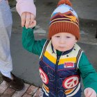 Child in layered clothes with toy robot and backpack in imaginative play setting