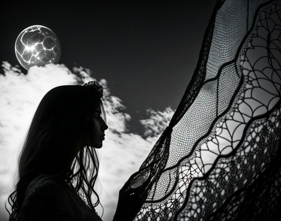 Silhouetted woman with tiara holding lace fabric under full moon