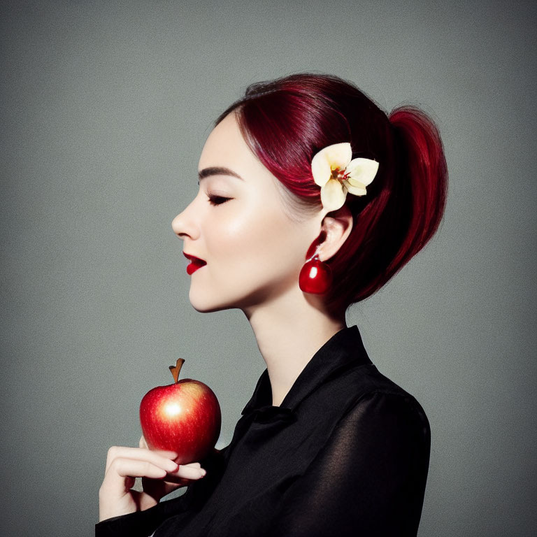 Red-haired woman in ponytail with apple, black outfit, red earrings, and white flower.