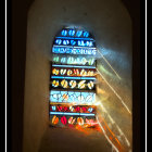 Colorful Patterns Illuminate Stone Wall in Stained Glass Window