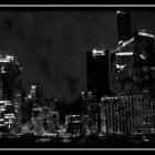 Monochromatic night cityscape with illuminated skyscrapers and water reflections