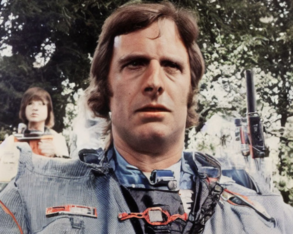 Futuristic man in blue uniform with intense gaze, woman in similar attire in background