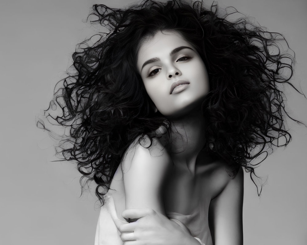 Monochrome portrait of young woman with voluminous curly hair.