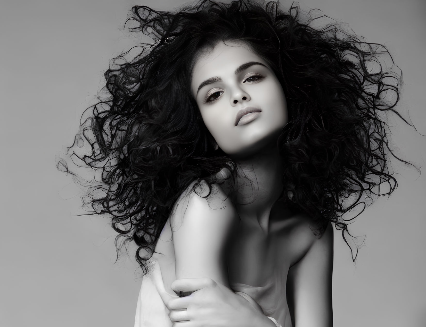 Monochrome portrait of young woman with voluminous curly hair.