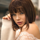 Digital artwork: Woman with short brown hair and striking makeup in white dress with gold accents against blurred natural