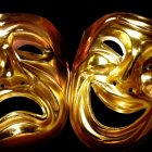 Golden theater masks: tragedy and comedy, intricate designs, glowing on dark background