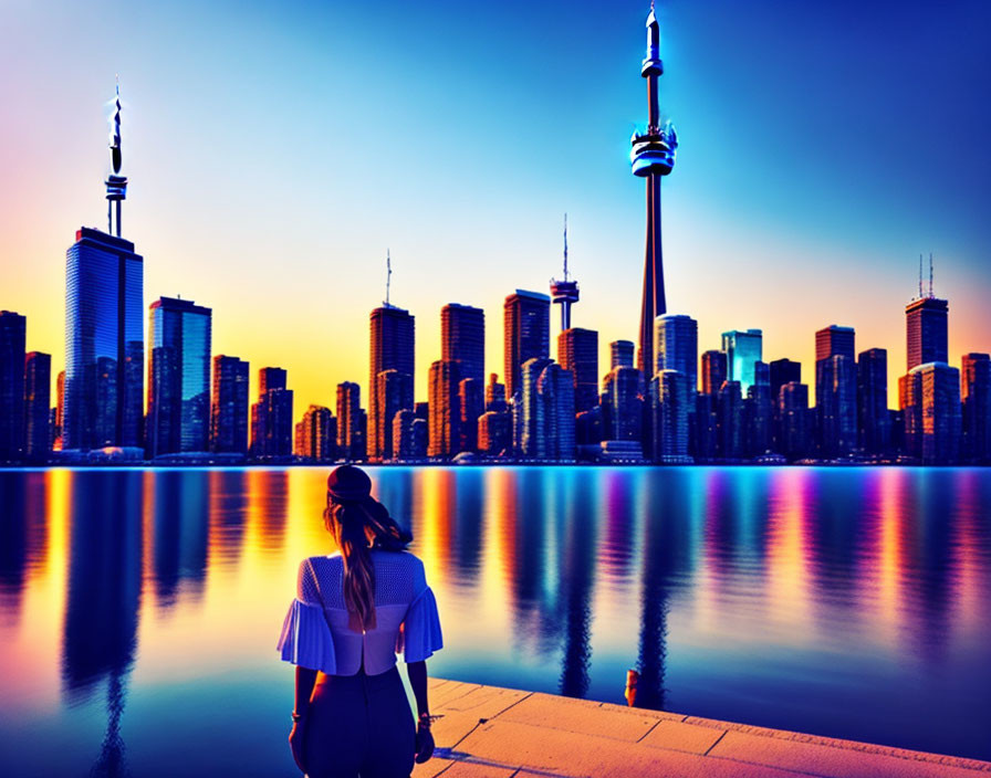 Person by calm lake at dusk with city skyline and tower silhouette.