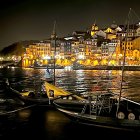 Coastal night scene: illuminated buildings, boats, starry sky