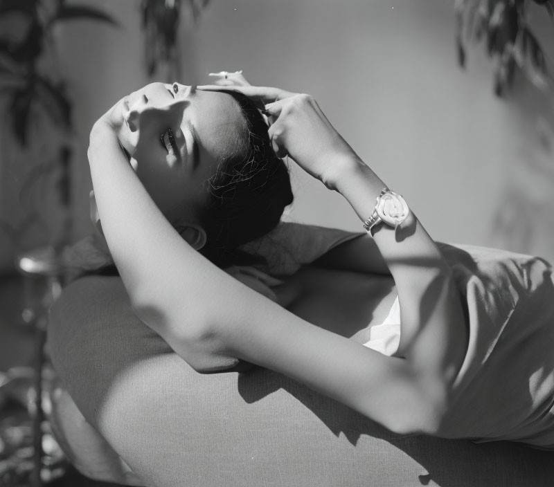 Monochrome photo of person lounging outdoors under dappled sunlight