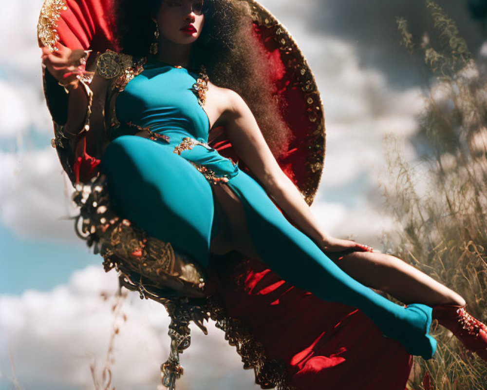 Woman in Teal and Red Outfit Lounging on Ornate Chair in Field