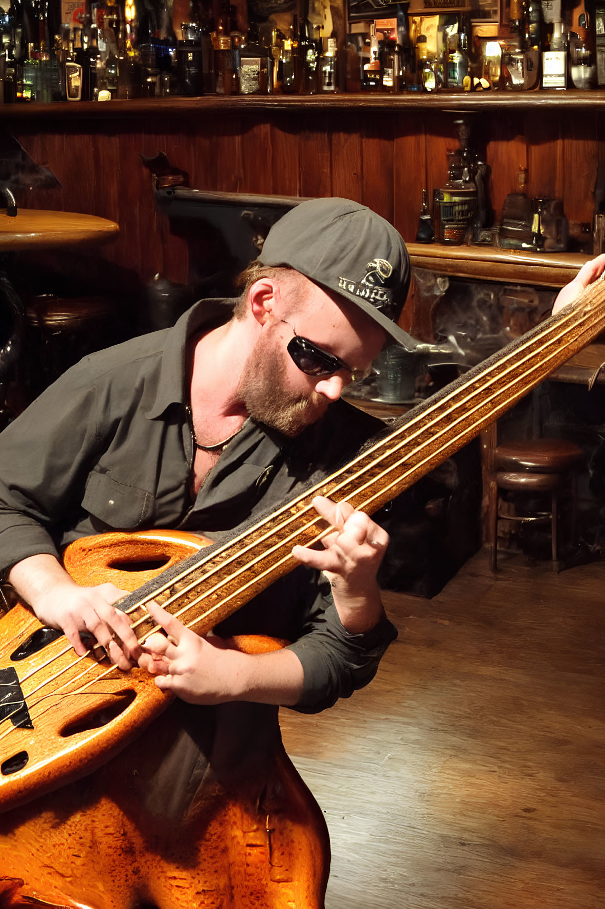 Musician playing electric bass guitar in bar with liquor bottles