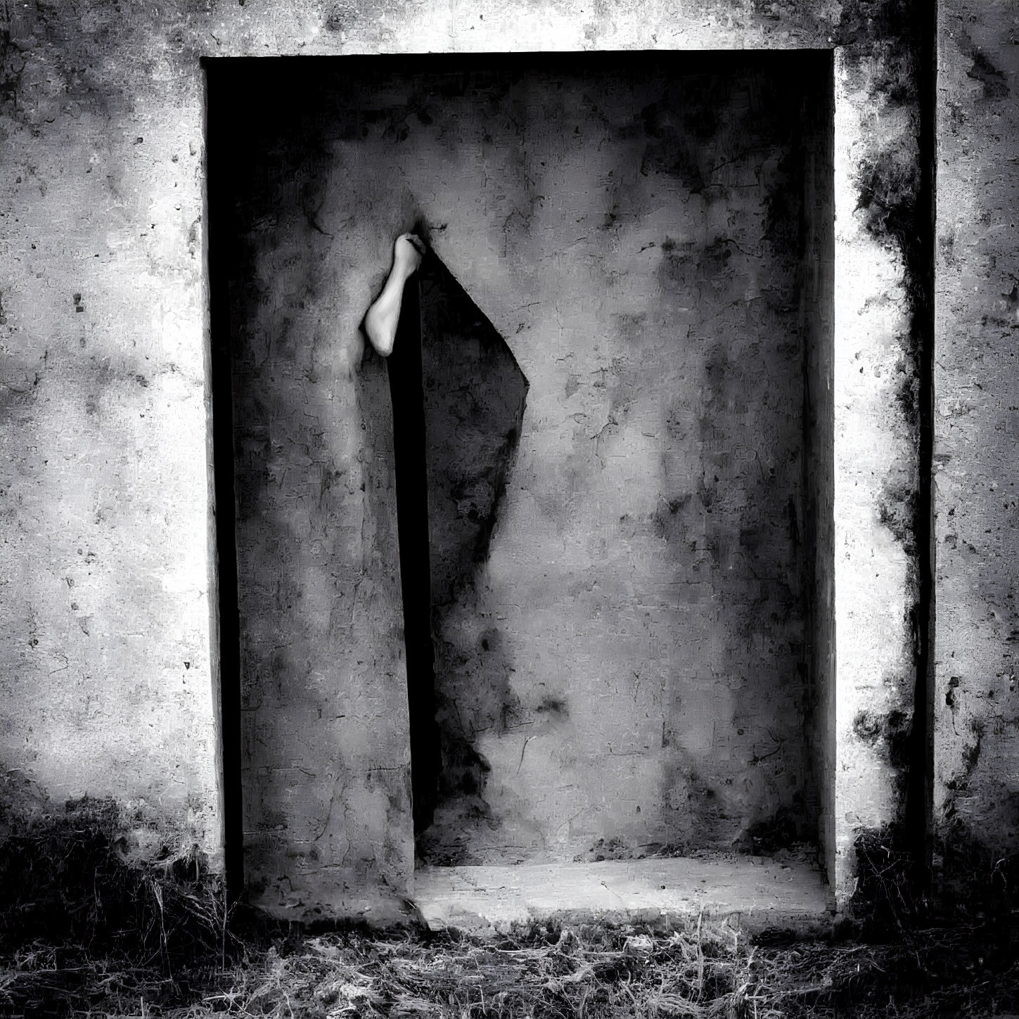 Monochrome image of textured wall with open doorway and human arm visible