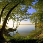 Tranquil Sunset Scene: Lake Reflections, Colorful Boat, Lush Trees