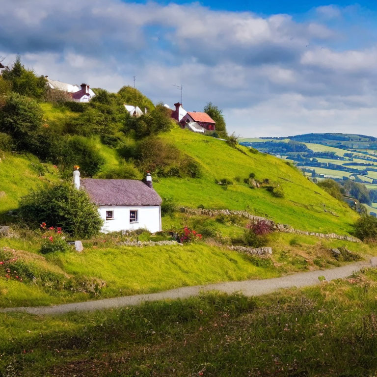 White cottages, red roofs on green hills under blue sky