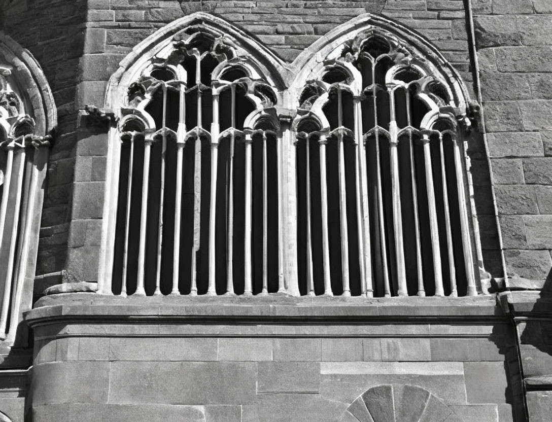 Monochrome image of Gothic-style arched windows on stone wall