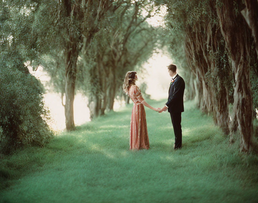 Couple Holding Hands on Grassy Path with Willow Trees