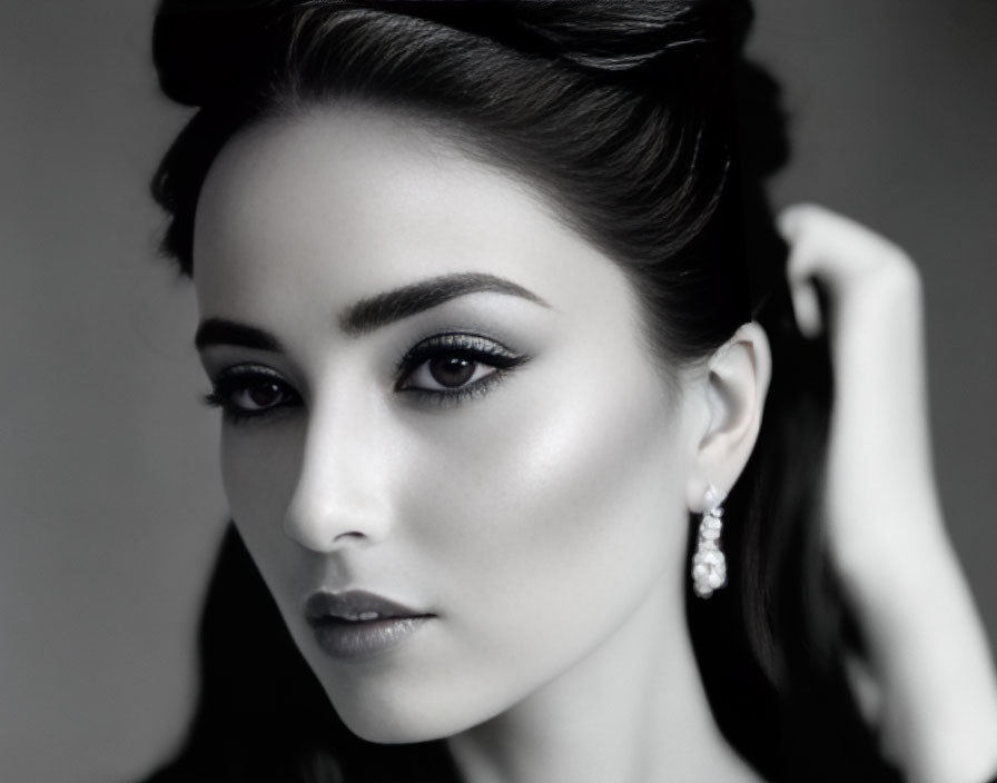 Monochrome portrait of woman with elegant makeup and updo hairstyle posing with stud earrings