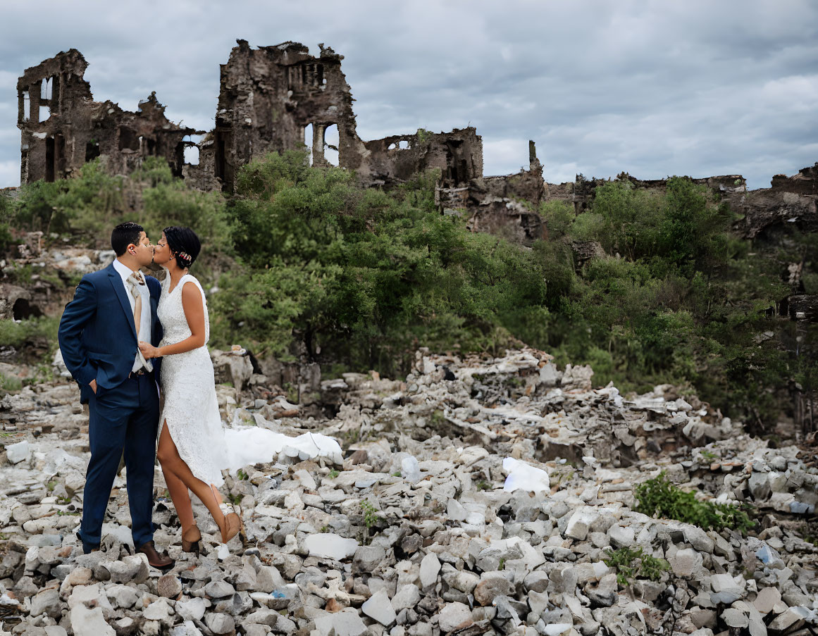 Wedding couple kissing in ruins under cloudy sky