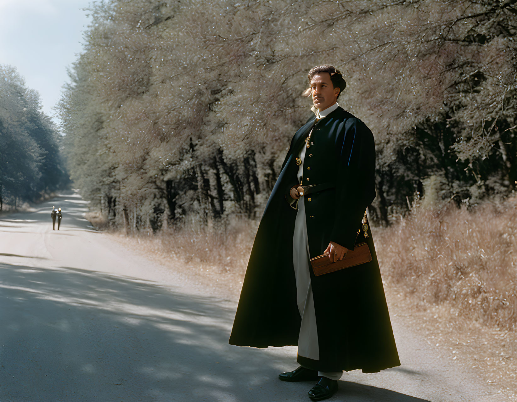 Man in vintage black coat stands on tree-lined path with book and dog