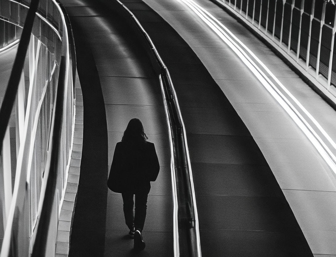 Monochrome image of lone figure on modern pedestrian walkway