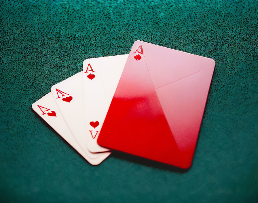 Four Ace Playing Cards with Hearts and Diamonds on Textured Green Surface