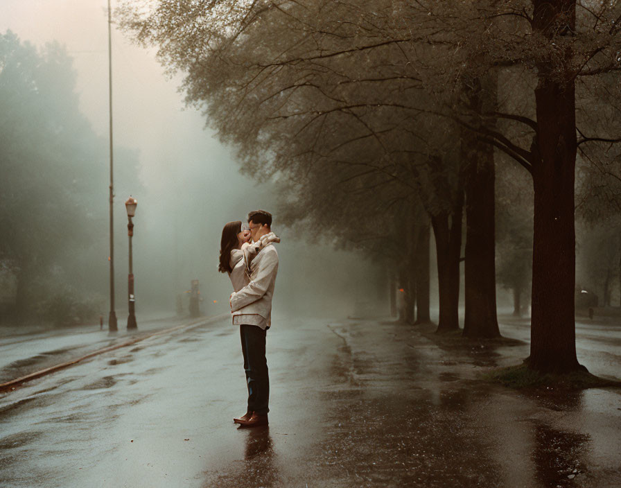 Couple standing on foggy tree-lined road with street lamps - romantic and mysterious ambiance