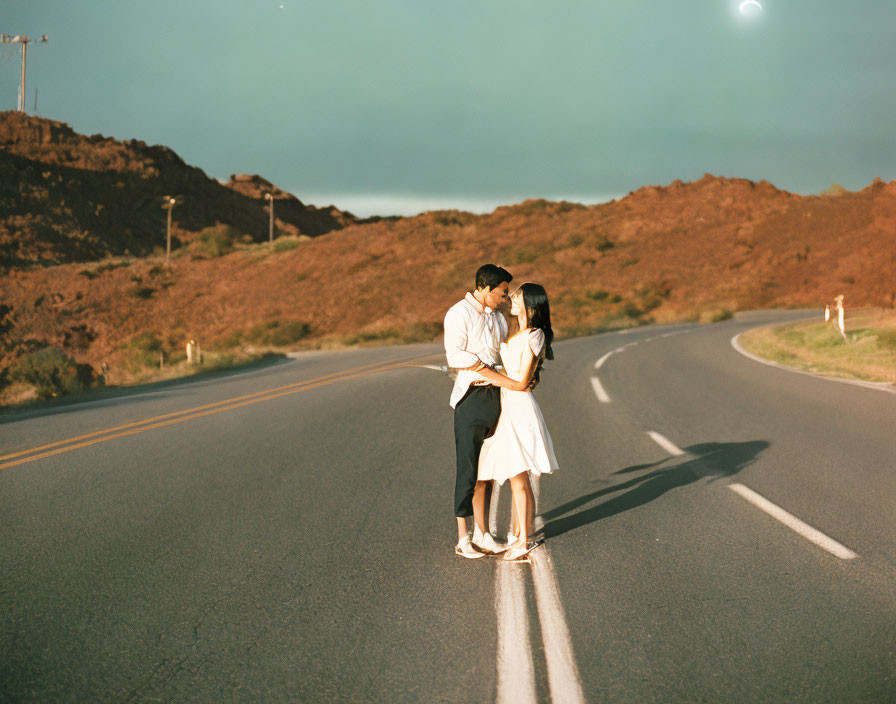 Couple kissing on deserted road at dusk