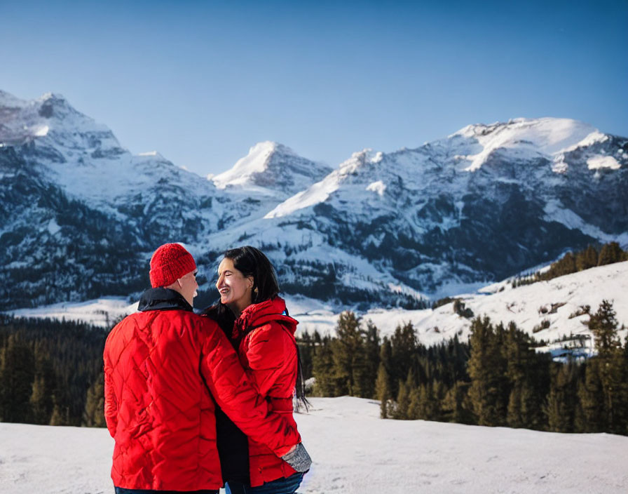 Couple in red jackets embrace in snowy mountain scene