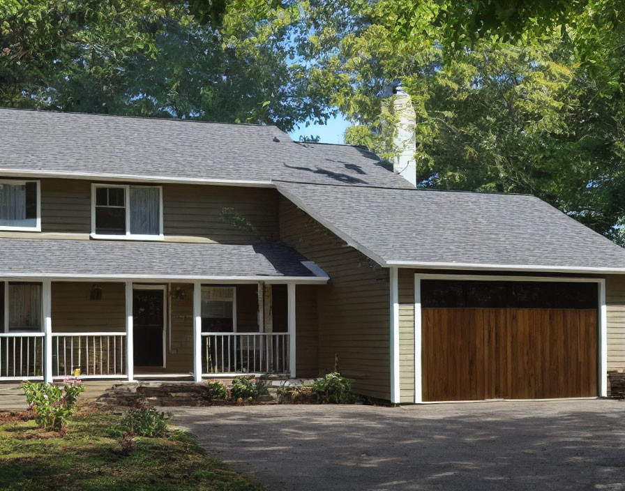 Two-story suburban home with wooden garage door and chimney on sunny day