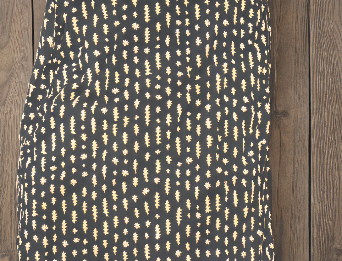 Black cloth with white batik-style patterns on dark wooden surface