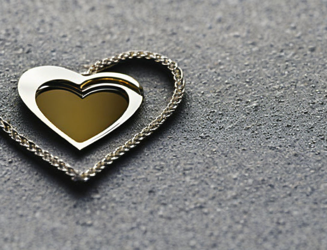 Silver Heart-Shaped Pendant with Golden Center on Textured Surface