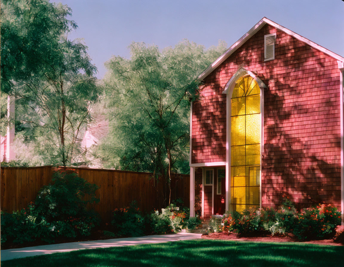 Quaint red house with large yellow stained glass window amid lush greenery