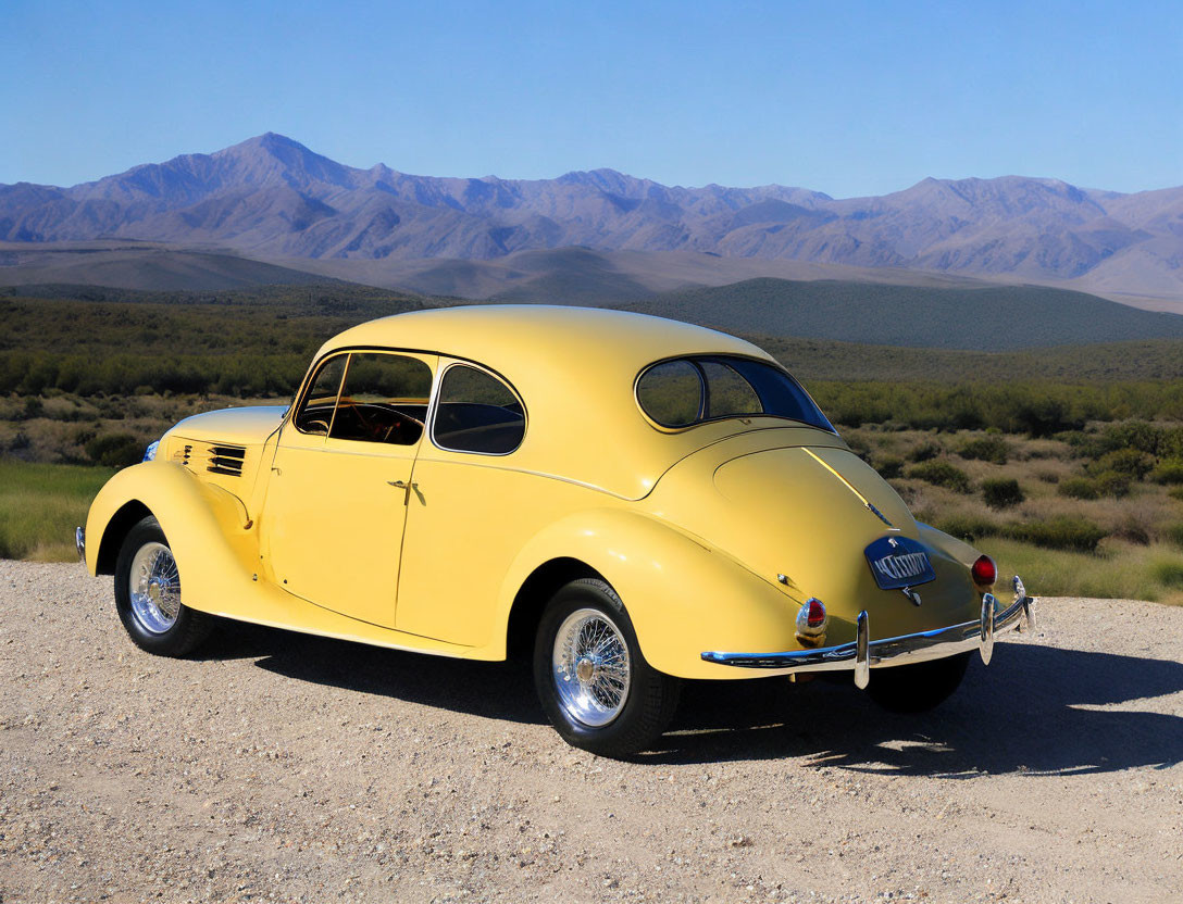 Vintage yellow car on desert road with mountains and blue sky