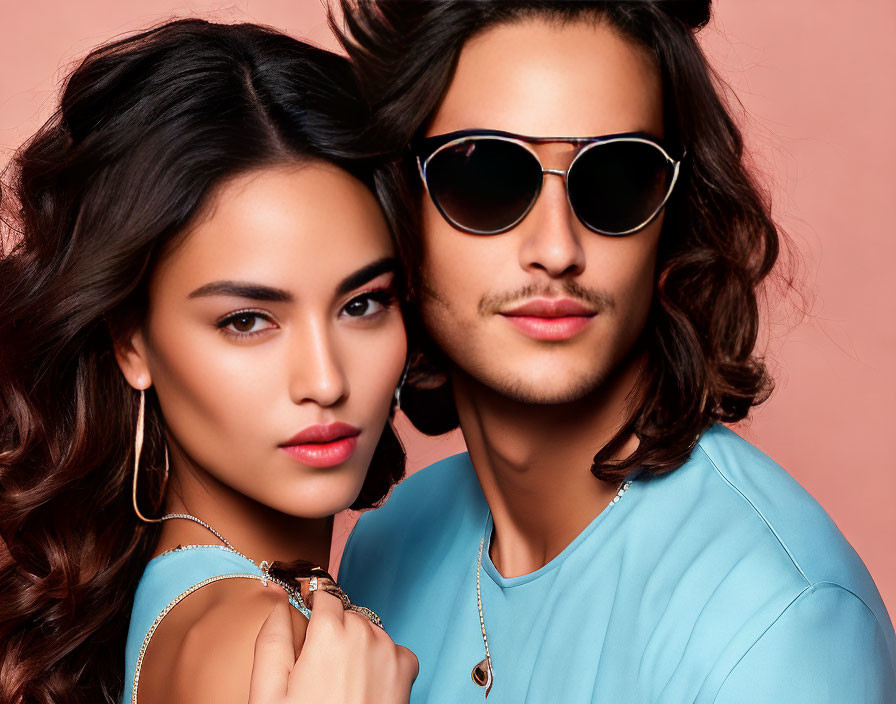 Woman and man in close-up shot, woman with bold makeup and earrings, man in sunglasses and blue